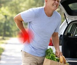 Man met een boodschappentas die zijn hand naar zijn onderrug brengt